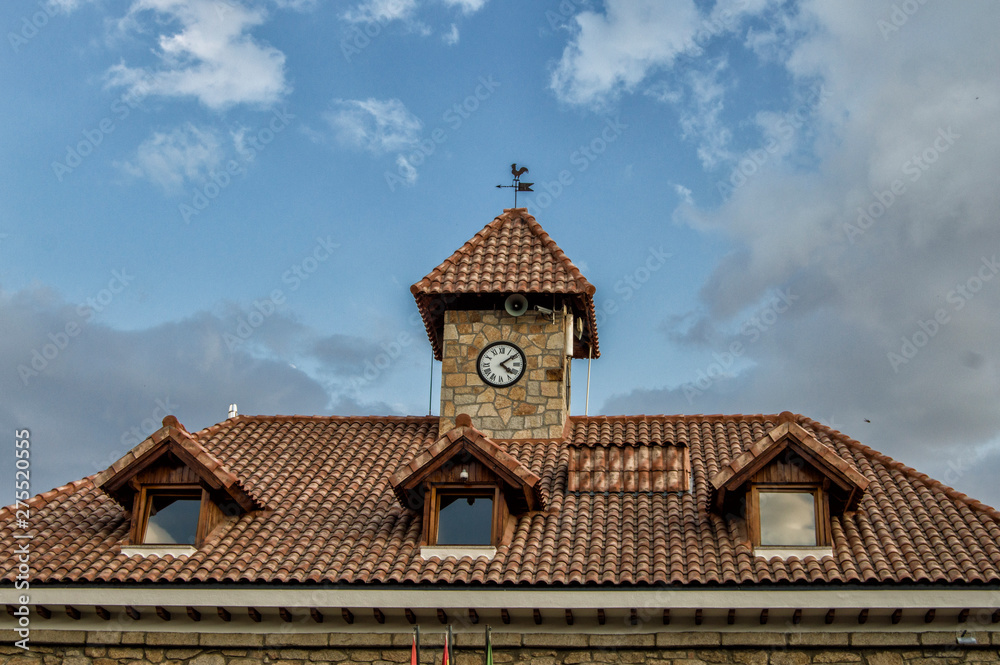 roof with three small windows and a tower with clock in a building roof with three small windows and a tower with clock in a building