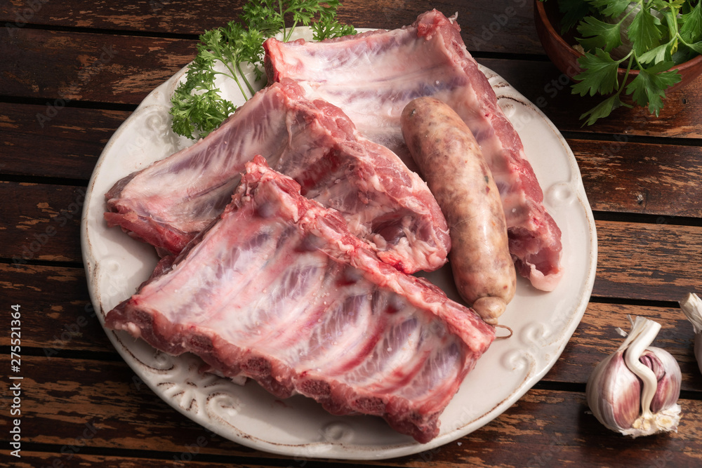 Fresh pork ribs and criollo sausage ready to be cooked on barbecue Fresh pork ribs and criollo sausage ready to be cooked on barbecue