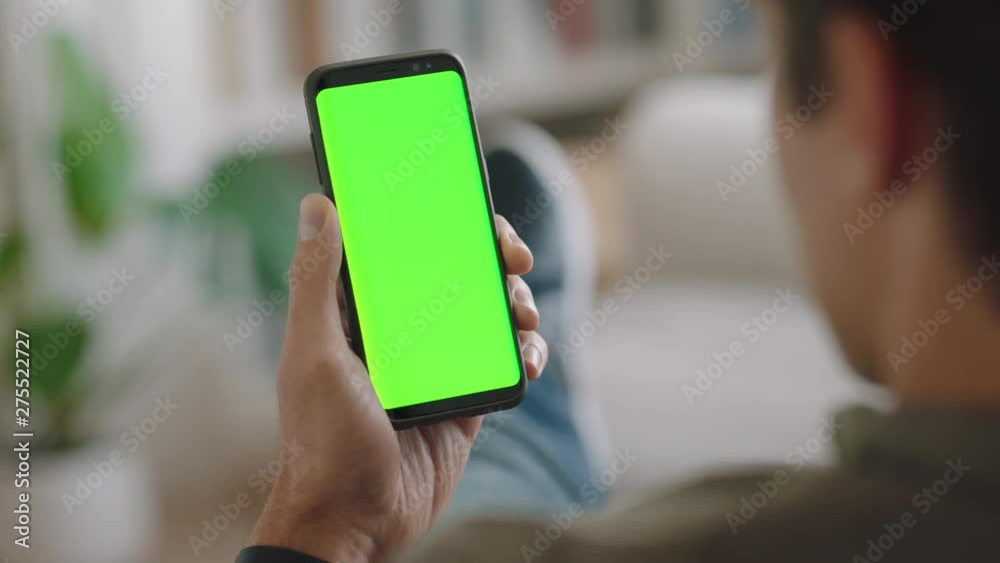 young man using smartphone watching green screen enjoying entertainment on mobile phone chroma key display horizontal orientation 4k footage