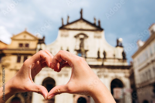 Girl showing heart shape love symbol over cityscape, Charles Bridge. Woman making heart shape with hands. Detail of the Old Town Bridge Tower in Prague, Czech Republic.