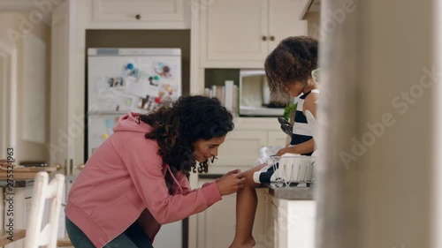 mother applying band aid to little girls knee caring for her child at home happy kid enjoying motherly love photo