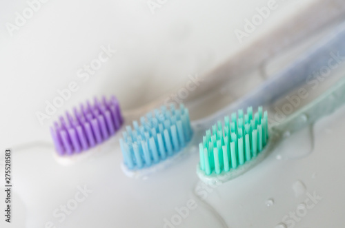 three toothbrushes of different colors on white background.