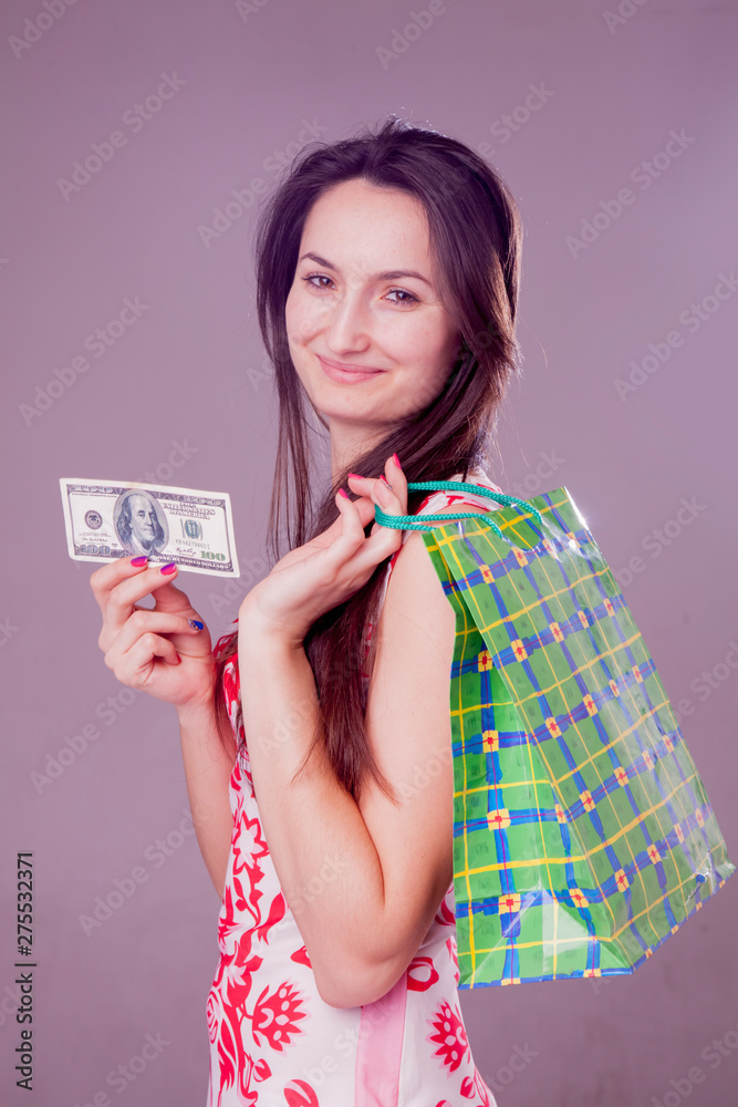 Image of a beautiful shocked happy woman with shopping bag holds US Dollar bill Image of a beautiful shocked happy woman with shopping bag holds US Dollar bill