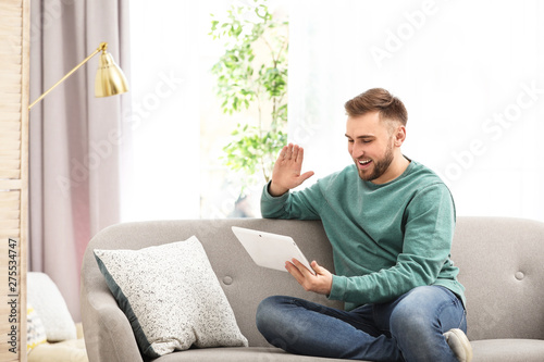 Young man using video chat on tablet in living room