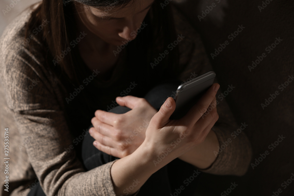 Sad woman using smartphone in dark room, closeup. Loneliness concept Sad woman using smartphone in dark room, closeup. Loneliness concept