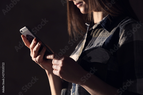 Woman using smartphone against dark background, closeup. Loneliness concept
