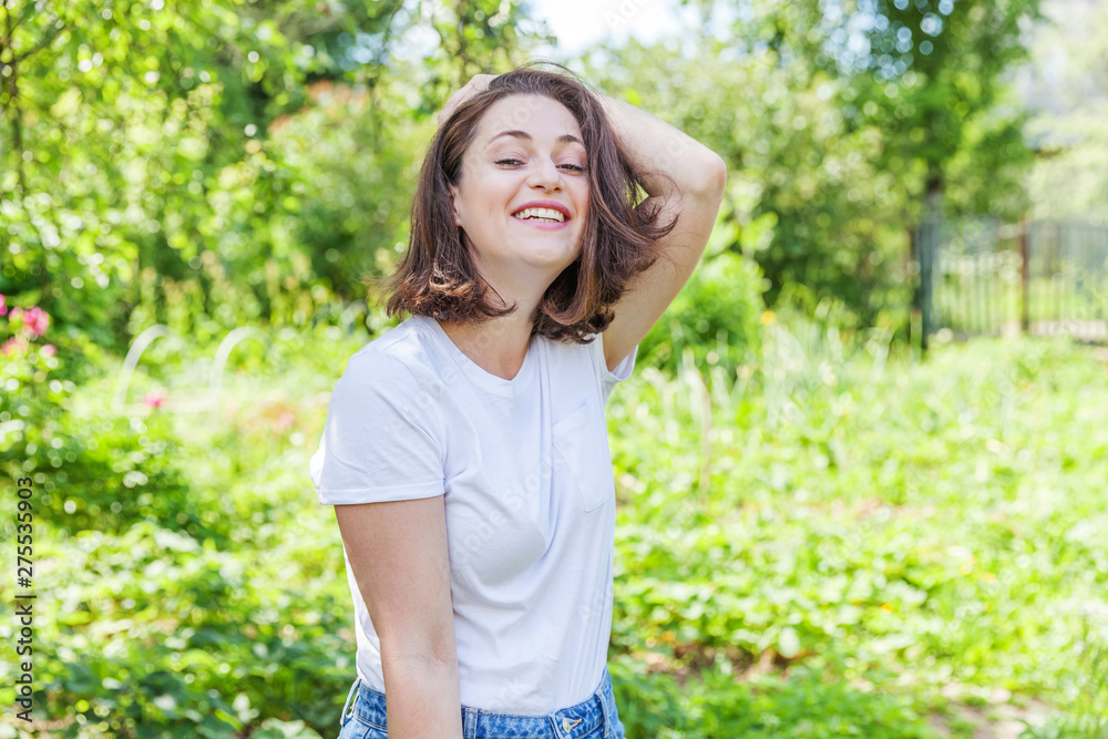 Happy girl smiling outdoor. Beautiful young brunete woman with brown hair resting on park or garden green background. European woman. Positive human emotion facial expression body language Happy girl smiling outdoor. Beautiful young brunete woman with brown hair resting on park or garden green background. European woman. Positive human emotion facial expression body language