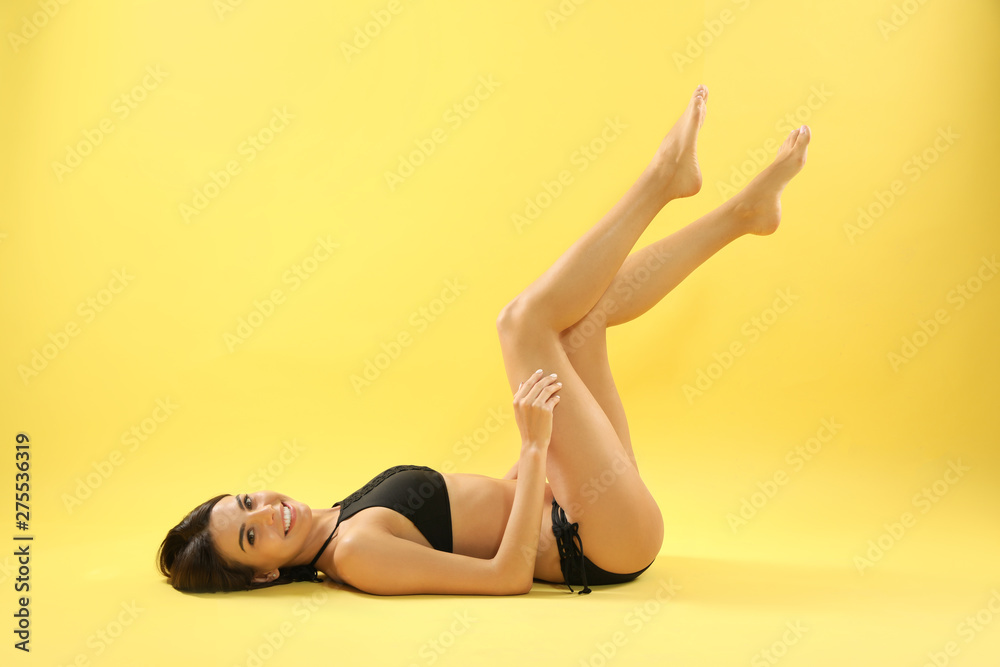 Full length portrait of attractive young woman with slim body in swimwear on color background