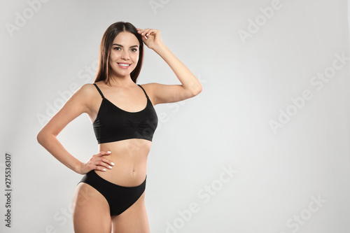 Portrait of attractive young woman with slim body in swimwear on white background. Space for text