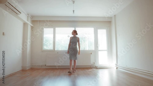 Young homeowner pretty woman is walking on empty house. Attractive girl is renter of house, install design of home. Real estate new agent viewing.