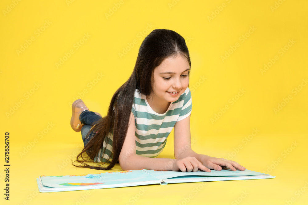 Cute little girl reading book on color background Cute little girl reading book on color background
