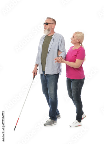 Mature woman helping blind person with long cane on white background