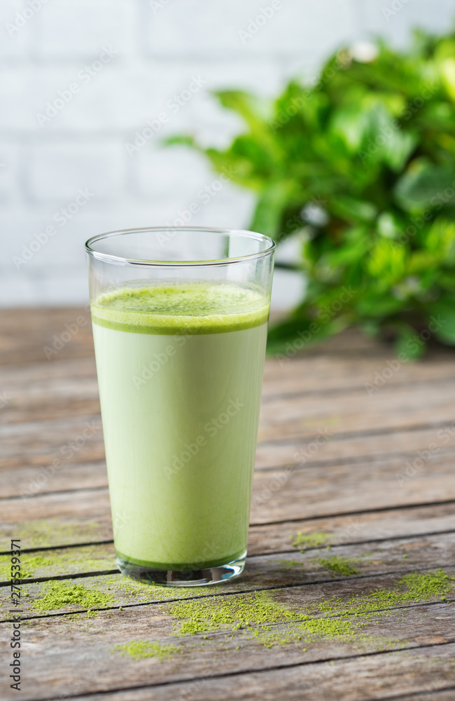 Glass of matcha green tea latte on a wooden table Glass of matcha green tea latte on a wooden table