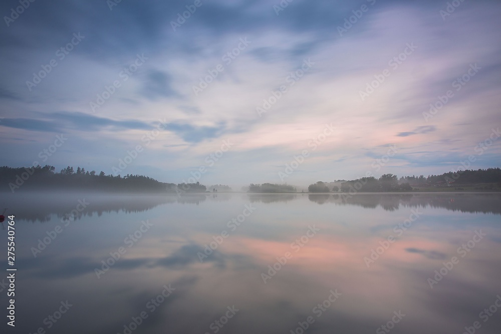 Gorgeous view of fog on sunset on lake on summer day. White clouds on blue sky. Europe. Sweden. Gorgeous backgrounds.
