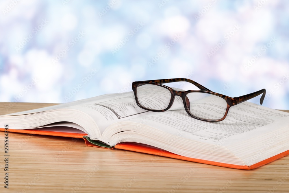 Close-up Black reading glasses and book on blurred library background