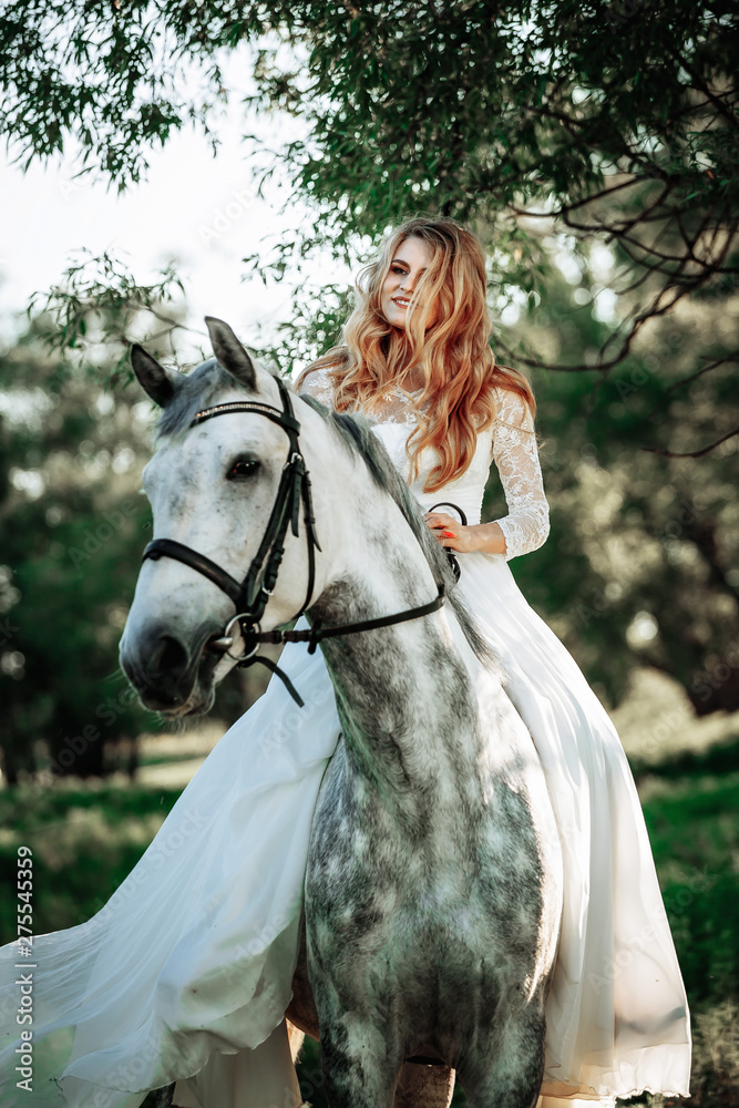 Fototapeta premium Beautiful and stunning bride, riding a horse in the nature