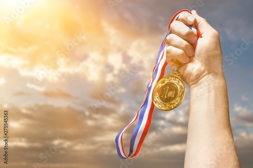 Gold medal with ribbon in hand on background