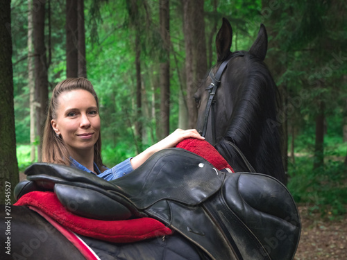 Beautiful girl smile at her horse. Outdoors portrait in green park