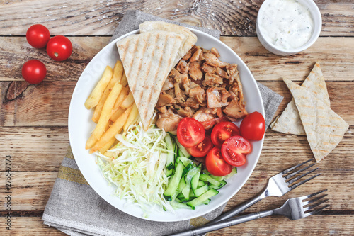 Greek gyros platter with french fries and vegetables.