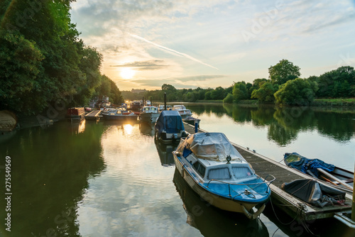 Boats moored on the docks along the river Thames in Twickenham West London early morning as the sun is rising.