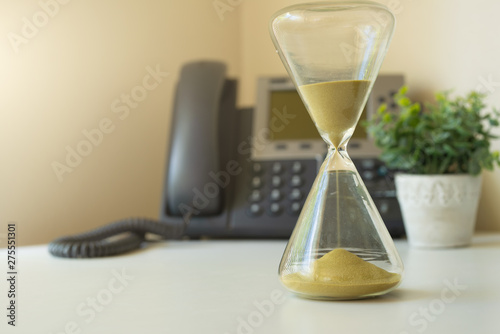 Hourglass on the background with phone, passing time concept, wet date or event