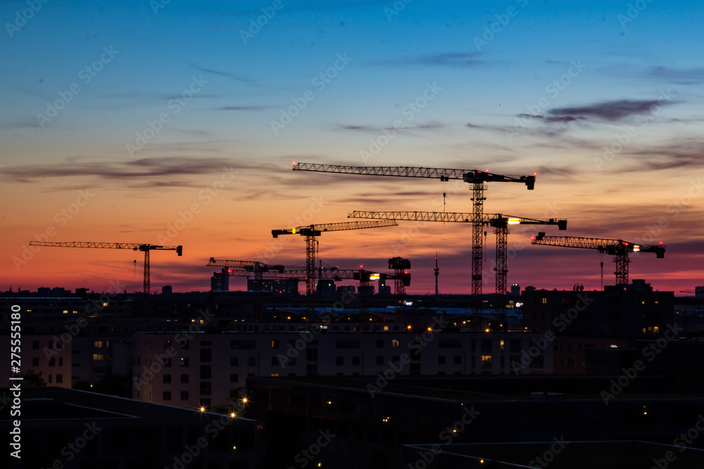 Construction cranes in the sunset in front of housing near the Munich trade fair area in Bavaria, Germany