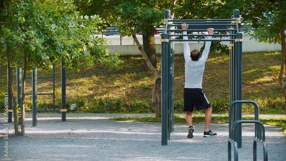 Fototapeta premium An athletic man hanging on the bar