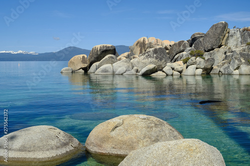 Large granite boulders sit in he shallow and clear waters of Lake Tahoe