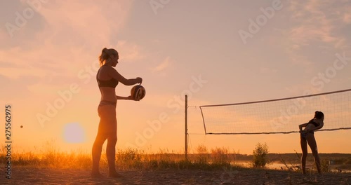 Beach volleyball serve - woman serving in beach volley ball game. Overhand spike serve. Young people having fun in the sun living healthy active sports lifestyle outdoors.