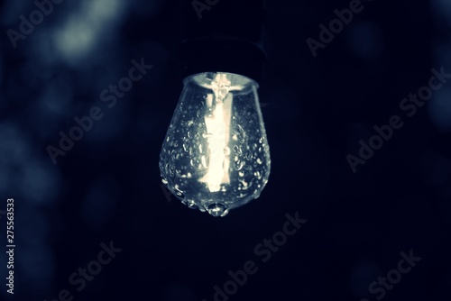 Close up on outdoor  lit lightbulb with droplets of rain on the glass © JMP Traveler