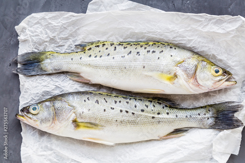 Fototapeta Naklejka Na Ścianę i Meble -  Fresh raw fish with spices, lemon, salt on dark stone background. Creative layout made of fish, top view with copy space, flat lay, mockup, overhead. Healthy food concept