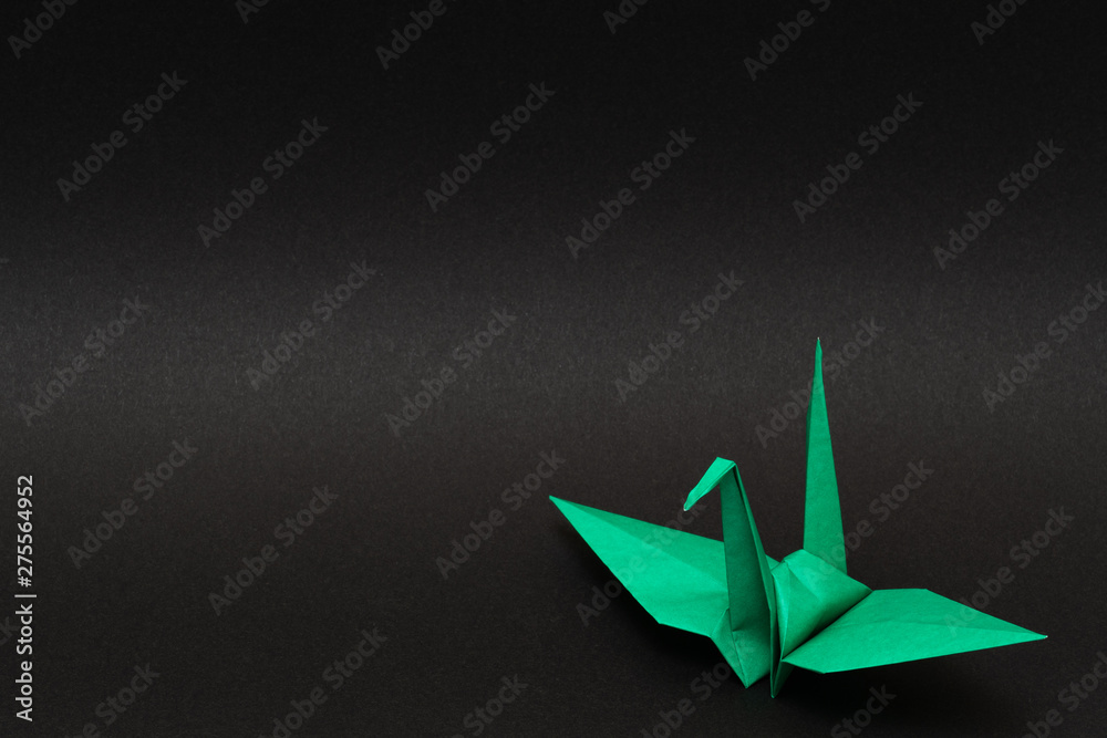 Naklejka premium green origami paper crane on black background