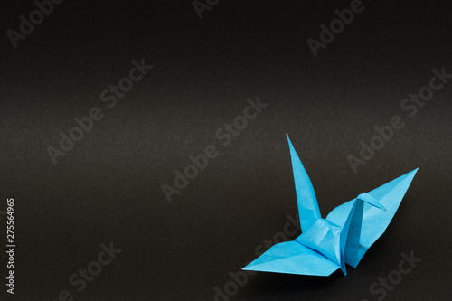 light blue origami paper crane on black background