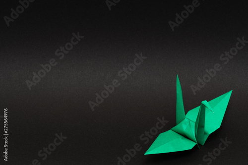 green origami paper crane on black background