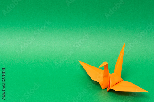orange origami paper crane on green background
