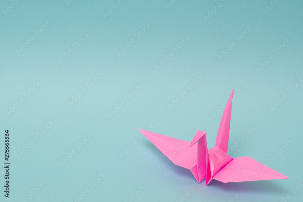 pink origami paper crane on sky blue background pink origami paper crane on sky blue background