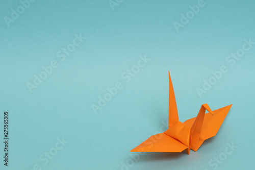orange origami paper crane on sky blue background