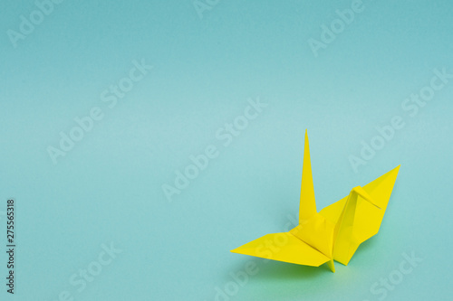 yellow origami paper crane on sky blue background