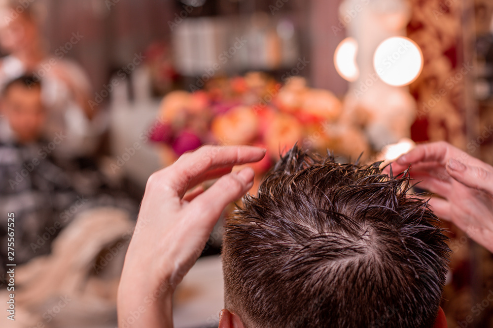 Φωτογραφία The master puts the hair of a man in a barbershop, a hairdresser makes a hairstyle for a young man with the help of gel and varnish