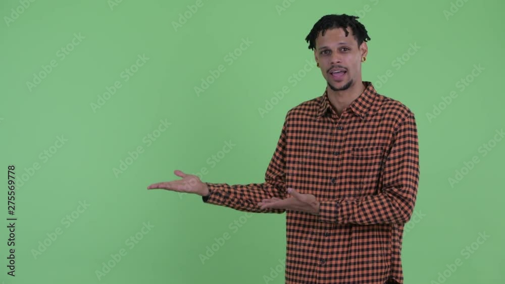Happy young handsome African man talking while showing something