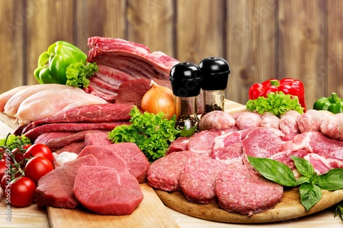 Fresh raw meat background with vegetables on wooden desk isolated on white background