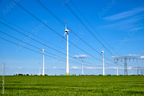 Power lines and wind engines on a sunny day seen in Germany © elxeneize