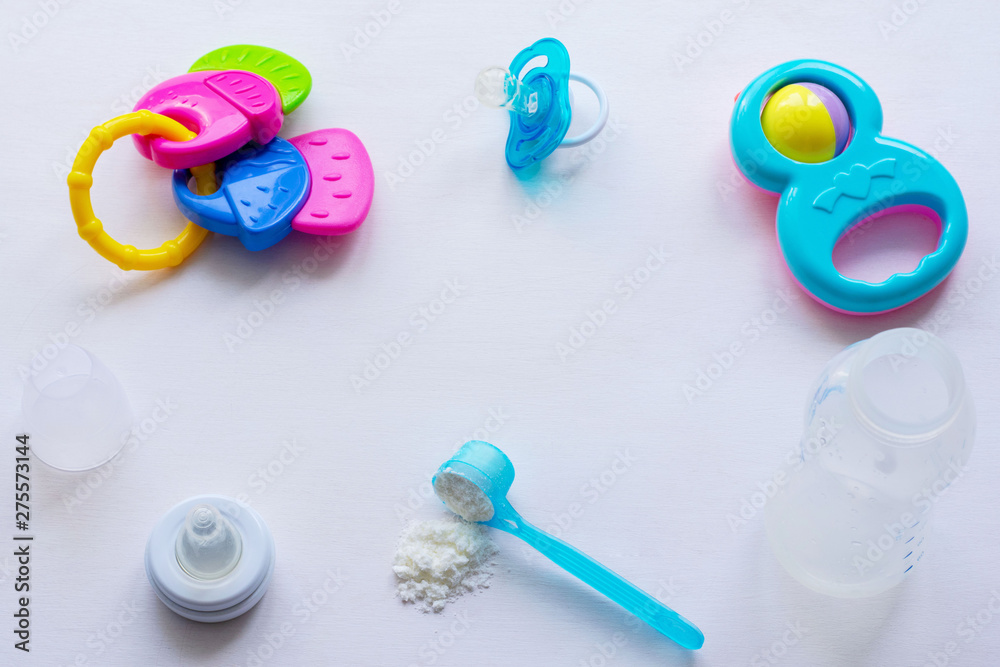 Baby milk powder, baby bottle and children's toys on a light background flat lay