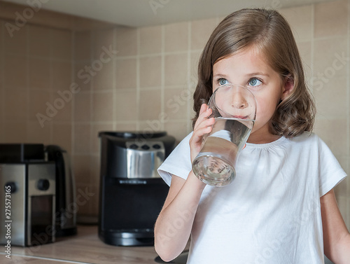 Slika na platnu Little child is drinking clean water at home, close up