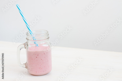 fresh cold pink smoothie on white background with blue straw 