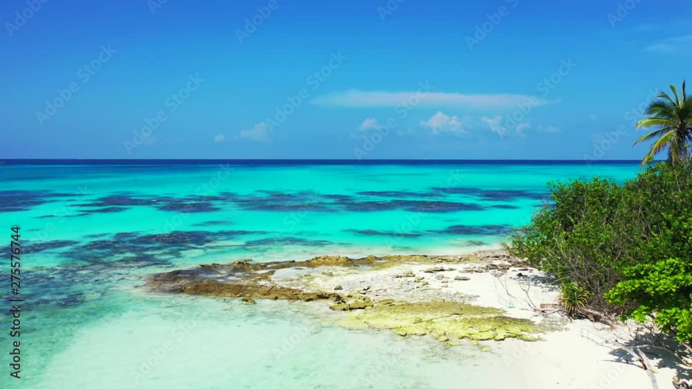 Aerial view, a tropical island with palm trees at a rocky beach. Turquoise water of the Philippines under a blue sky with clouds. Truck left