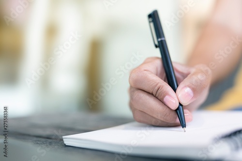 Women holding a pen writing a notebook. Recording and business concept.