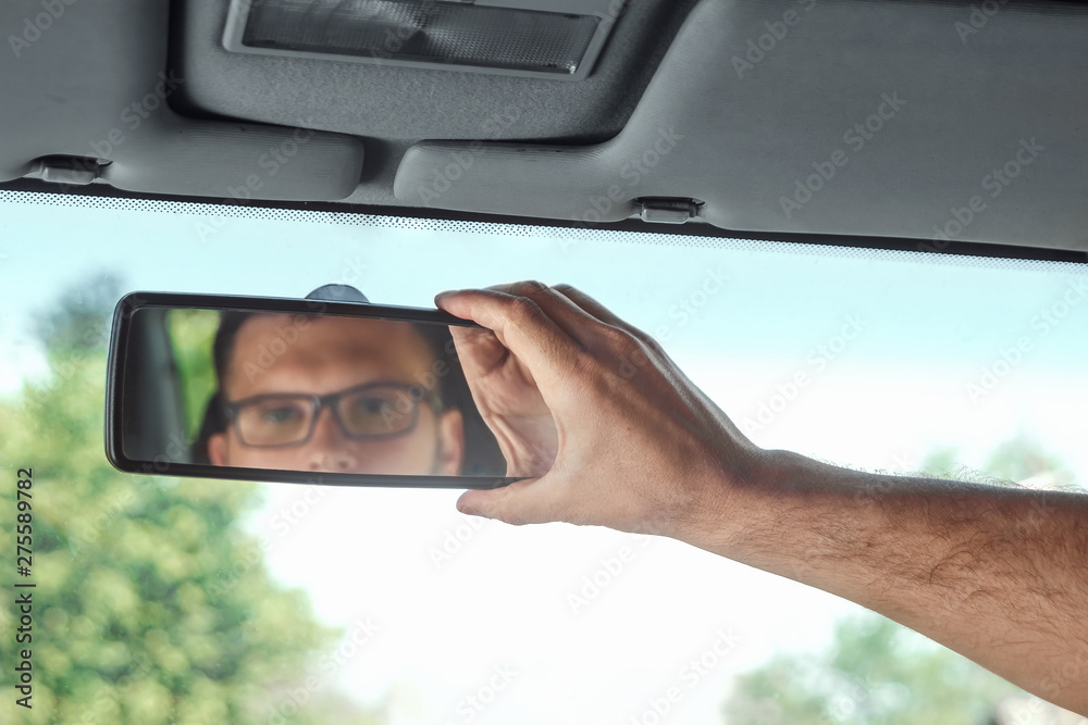 Male hand on the rearview mirror of a car, close-up. Manual adjustment of a rear-view mirror