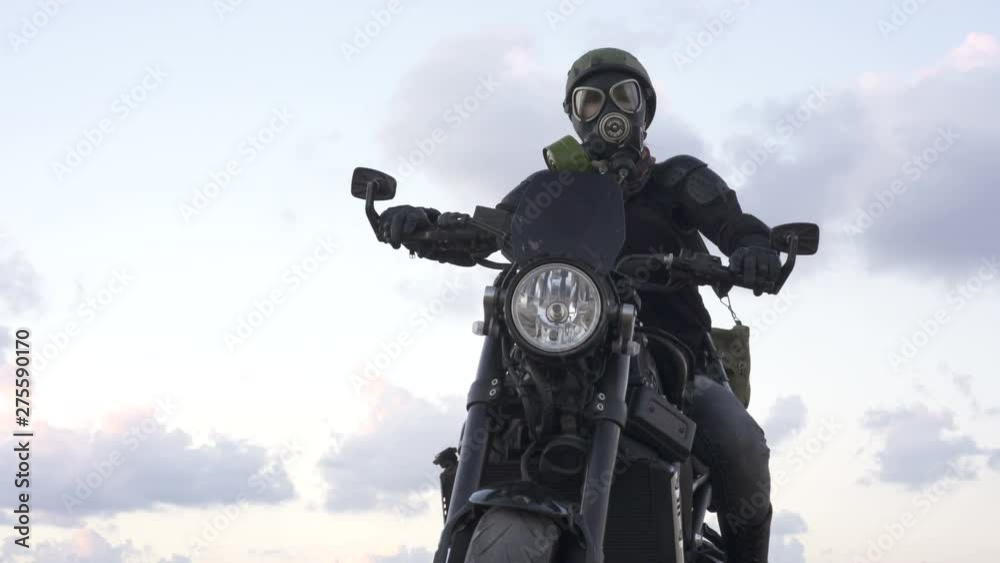 Biker woman with a pollution mask in army helmet on Motorcycle  on the old desert  road. Concept You say No War