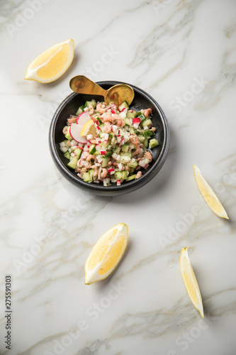 Norddeutscher Friesischer Nordseekrabben Salat in Schale mit Gurken, Radieschen, Zwiebeln, Dill und Zitronen auf Marmor Tisch photo